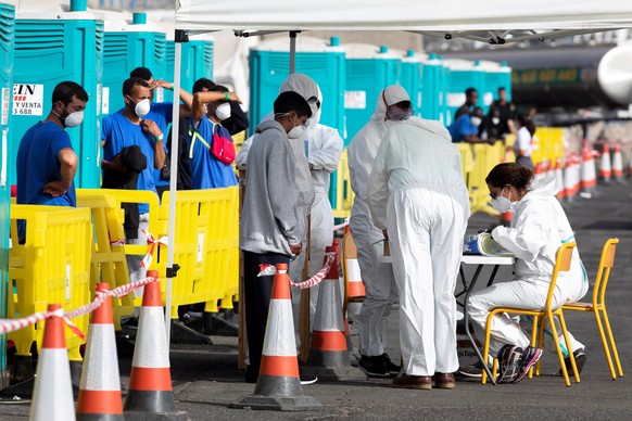 epa08690468 Dozens of African migrants are queuing so as to check some data with health personnel at the dock in Arguineguin, southwest of Gran Canaria, the Canaries, Spain, 23 September 2020. This do ...