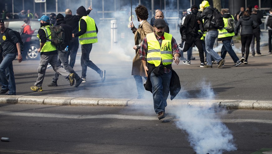 epa07489216 Protesters from the &#039;Gilets Jaunes&#039; (Yellow Vests) movement run through tear gas during the &#039;Act XXI&#039; demonstration (the 21st consecutive national protest on a Saturday ...