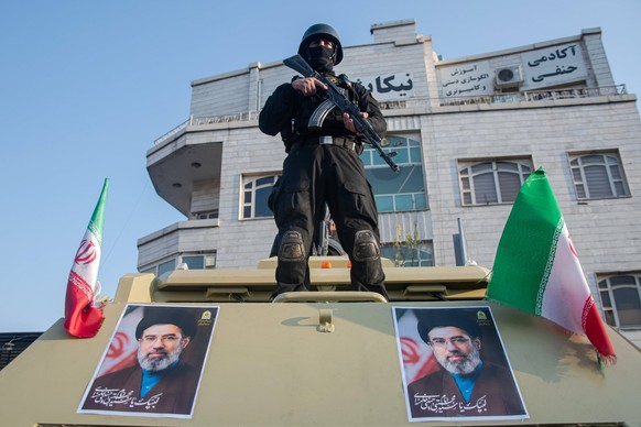An Iranian security officer stands atop an armored vehicle adorned with portraits of the new Supreme Leader Mojtaba Khamenei during a march on Revolution Street in Tehran, Iran, Monday, March 9, 2026. ...
