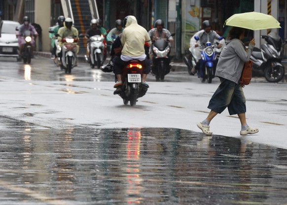 epa12252490 A woman (R) protects herself from drizzle as she walks on a road in Bangkok, Thailand, 22 July 2025. The Thai Meteorological Department issued a public warning, as Tropical Storm Wipha is  ...