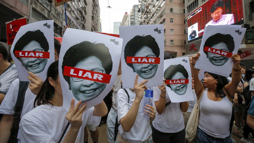 Protesters hold pictures of Hong Kong Chief Executive Carrie Lam as protesters march along a downtown street against the proposed amendments to an extradition law in Hong Kong Sunday, June 9, 2019. A  ...