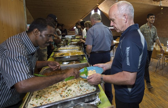 Bundesrat Ueli Maurer lässt sich von einem Asylsuchenden bei einer zweitätigen Bundesratsreise Essen schöpfen. 