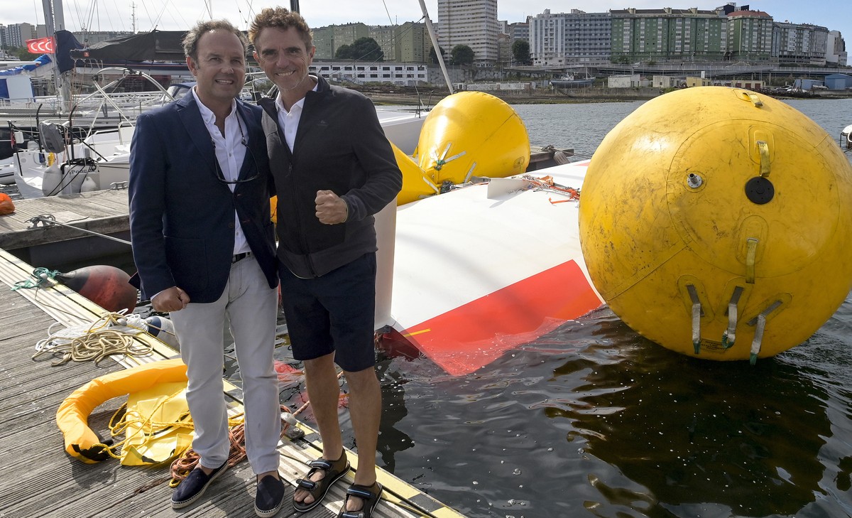 epa10104465 French sailor Laurent Camprubi (R) pose with Chief of Maritime Rescue Finisterre, Manuel Capeans (R) next to the overturned sailboat moored at Oza's port in La Coruna, Galicia, nortwe ...