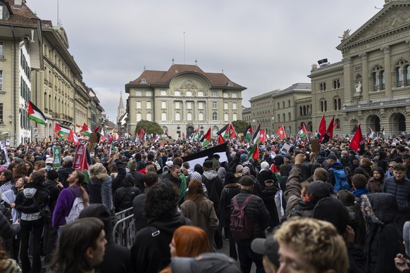 People hold banners and wave Palestinian flags on the Federal Square (Bundesplatz) in front of the parliament building (Bundeshaus) during an unauthorized rally in solidarity with the Palestinian peop ...