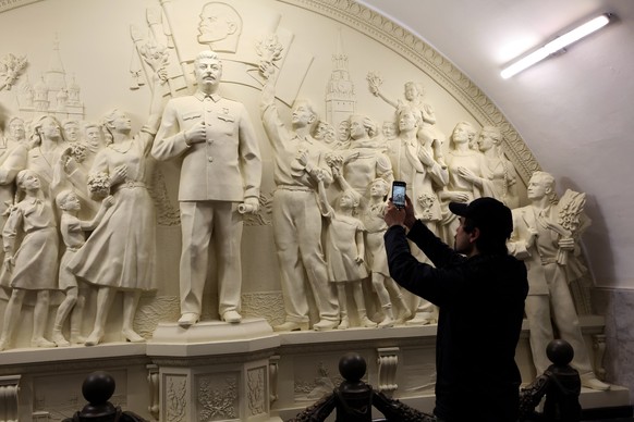 epa12102622 A man takes a photo with a mobile phone of the replica of the high relief of Soviet leader Joseph Stalin during celebrations of the 90th anniversary of Moscow Metro at the Taganskaya metro ...