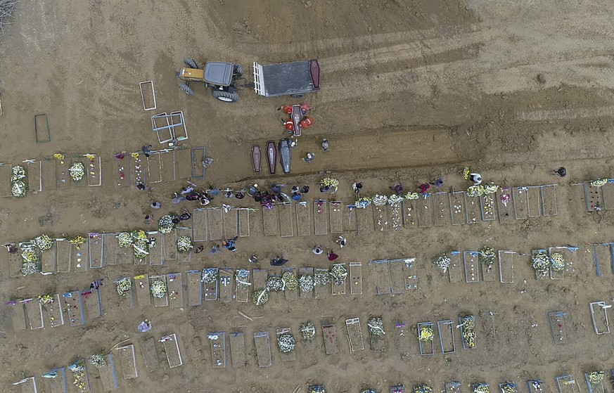 Workers carry a coffin into a common pit at the Nossa Senhora Aparecida cemetery, amid the new coronavirus pandemic in Manaus, Amazonas state, Brazil, Wednesday, April 22, 2020. (AP Photo/Emerson Card ...