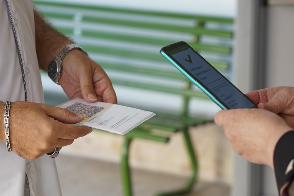 A teacher, left, has her so-called &quot;Green Pass&quot; checked by a school worker as she arrives at the &quot;Isacco Newton&quot; high school, in Rome, Monday, Sept. 13, 2021. After most of the las ...