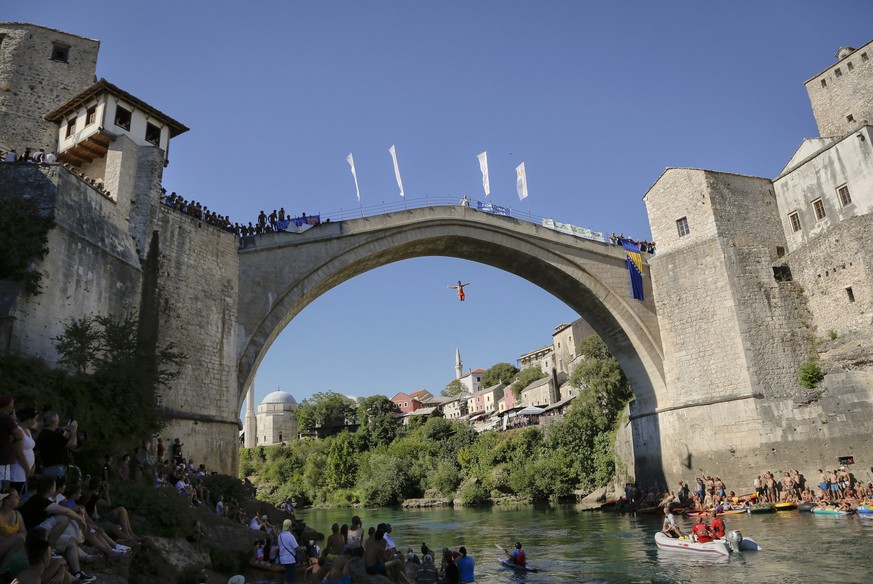 In this photograph taken on Sunday, July 30, 2017, spectators watch men jump from the Old Bridge in Mostar, Bosnia, during an annual diving competition that has been drawing crowds for more than 4.5 c ...