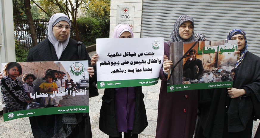 Frauen in Madaya halten Plakate von Hungernden hoch.