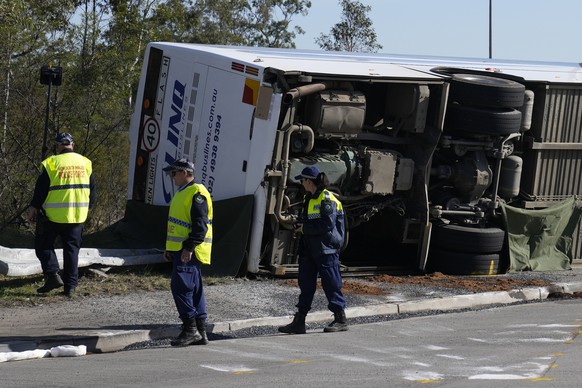 Police inspect a bus in its side near the town of Greta following a crash in the Hunter Valley, north of Sydney, Australia, Monday, June 12, 2023. The bus carrying wedding guests rolled over on a fogg ...