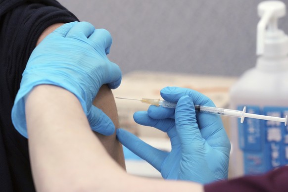 In this June 21, 2021, file photo, a resident receives a Moderna COVID-19 vaccine shot at their office in Tokyo. Tokyo&#039;s COVID-19 infections surged to a six-month high Wednesday, July 21, 2021, w ...