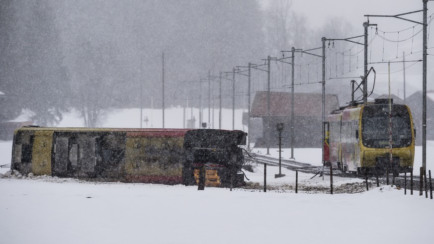 Workers walk past a derailed coache of the GoldenPass train of the Company Montreux-Oberland Bernois (MOB) at the scene of a train crash in Boden near Lenk, in the Canton of Bern, Switzerland, Wednesd ...