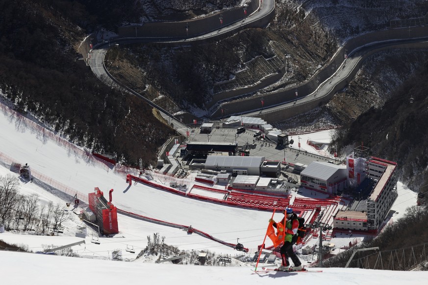 A course worker removes a flag from a gate on the men&#039;s downhill course after race was postponed due to high winds at the 2022 Winter Olympics, Sunday, Feb. 6, 2022, in the Yanqing district of Be ...