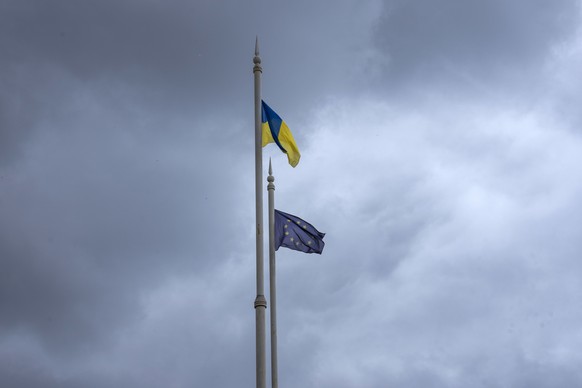 The Ukrainian flag, left, and EU flag fly on poles, in Kyiv, Ukraine, Thursday, June 23, 2022. European Union leaders on Thursday are set to grant Ukraine candidate status to join the 27-nation bloc, a first step in a long and unpredictable journey toward full membership that could take many years to achieve. (AP Photo/Nariman El-Mofty)