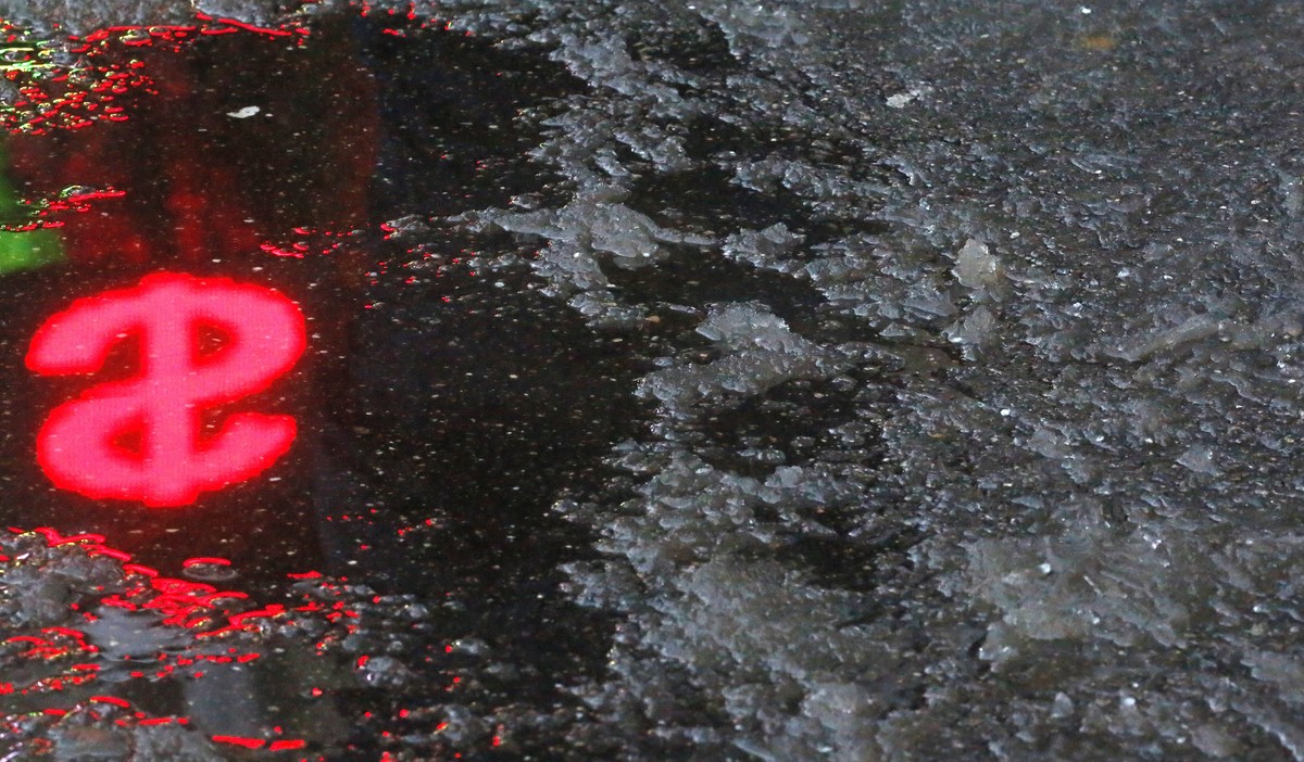 epa10376393 A US Dollar symbol is reflected in melted ice outside a currency exchange office in Moscow, Russia, 22 December 2022. At the opening of trading on the Moscow Exchange, the exchange rate re ...