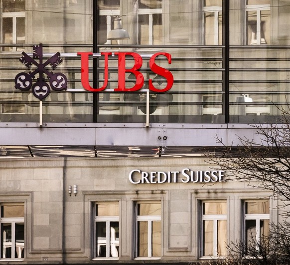 Logos of the Swiss banks Credit Suisse and UBS are seen next to traffic lights on two buildings in Zurich, Switzerland on Saturday, March 18, 2023. (KEYSTONE/Michael Buholzer).