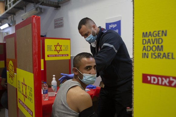 A Palestinian worker receives the Moderna coronavirus vaccine at the Hashmonim checkpoint between the West Bank and Israel, near the Israeli West Bank settlement of Nili, Monday, March 8, 2021. After  ...
