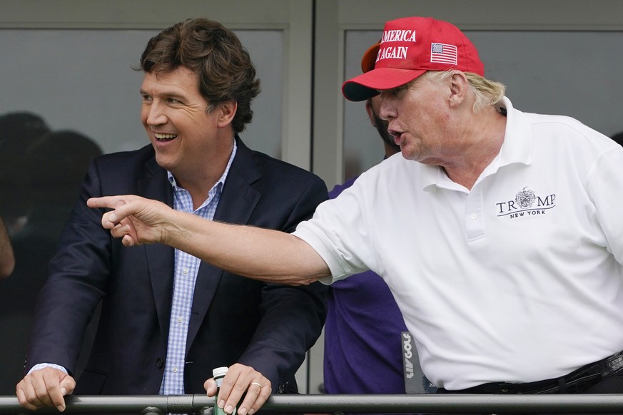 Tucker Carlson, left, and former President Donald Trump, talk while watching golfers on the 16th tee during the final round of the LIV Golf Invitational at Trump National in Bedminster, N.J., July 31, ...