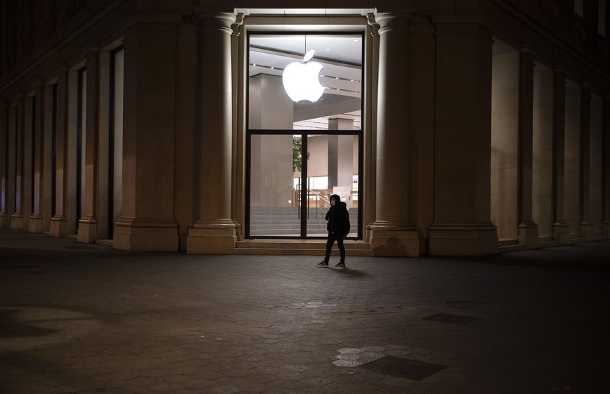 A man wearing a face mask walks past a closed Apple store during a nationwide confinement to counter the new coronavirus in Barcelona, Spain, Tuesday, April 7, 2020. The new coronavirus causes mild or ...