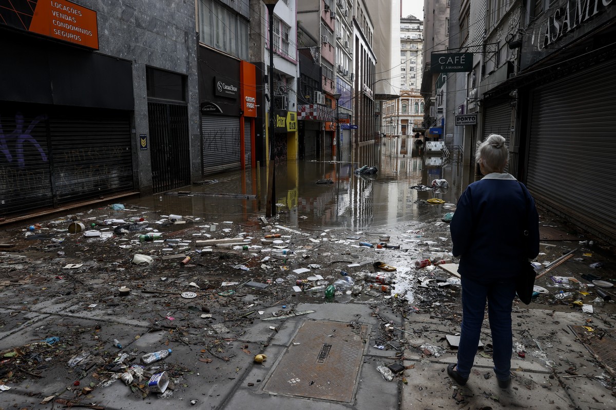 epa11337712 A woman observes a flooded street with water and garbage in the commercial center in Porto Alegre, Brazil, 13 May 2024. The Brazilian city of Porto Alegre has been flooded for ten consecut ...