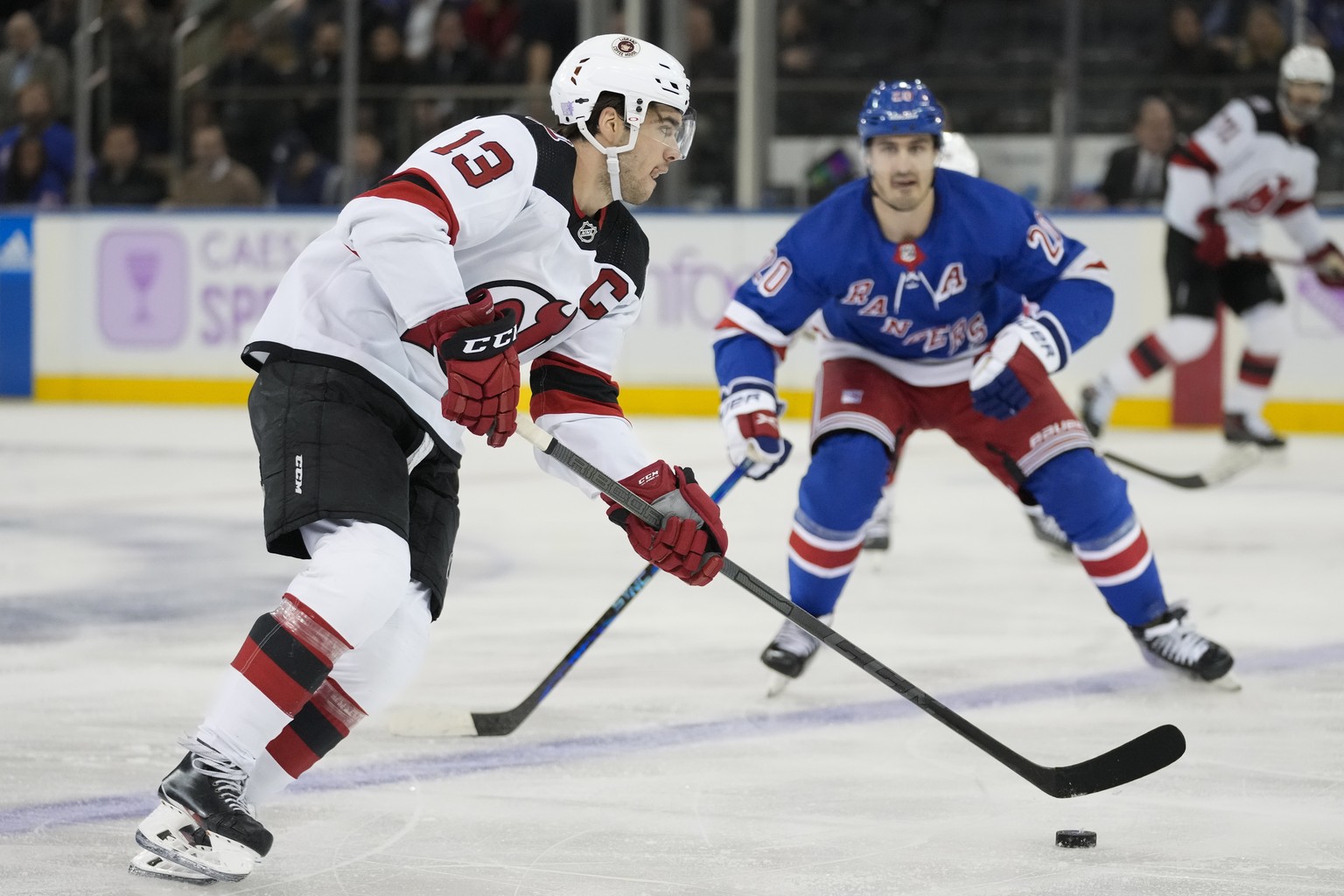 New Jersey Devils center Nico Hischier (13) looks to pass against New York Rangers left wing Chris Kreider (20) in the second period of an NHL hockey game, Monday, Nov. 28, 2022, in New York. (AP Phot ...