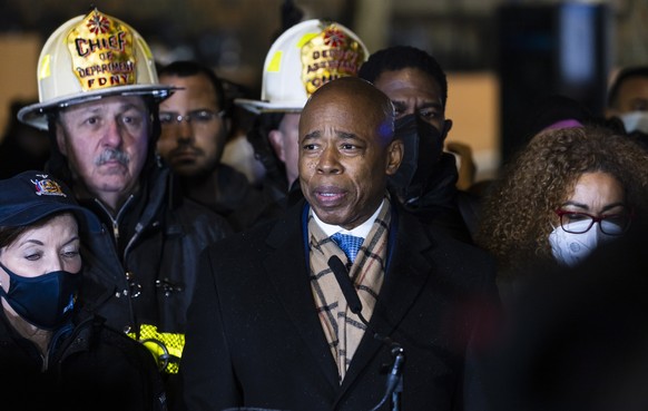 epa09676440 New York City Mayor Eric Adams (C) talks to reporters while standing with New York Governor Kathy Hochul (L) and New York City Fire Department officials at the scene of a 5-alarm apartment ...