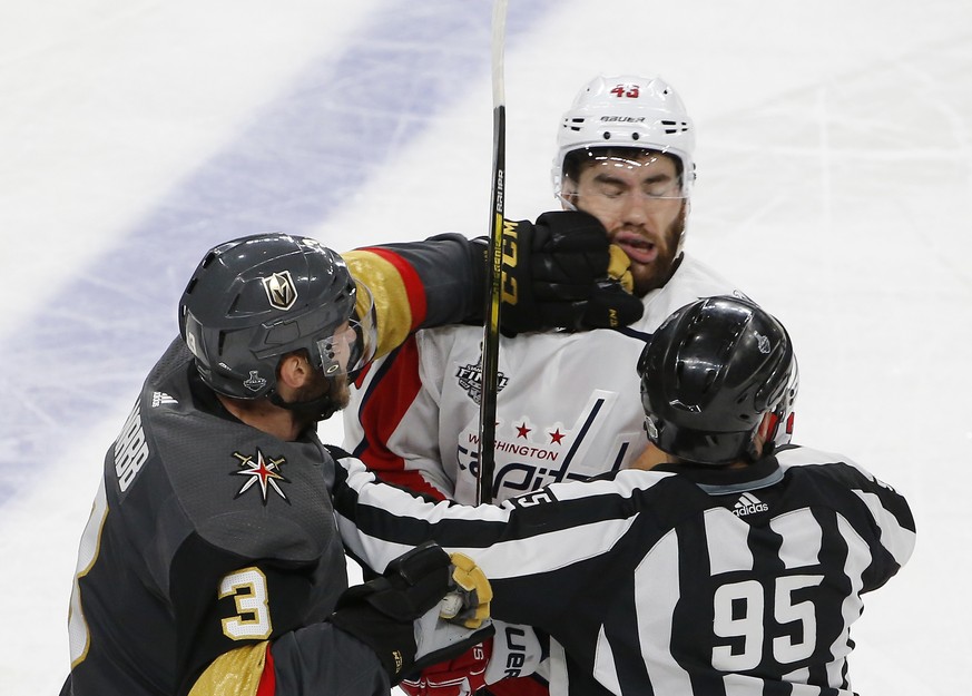 Vegas Golden Knights defenseman Brayden McNabb, left, hits Washington Capitals right wing Tom Wilson as linesman Jonny Murray tries to break it up during the third period in Game 1 of the NHL hockey S ...