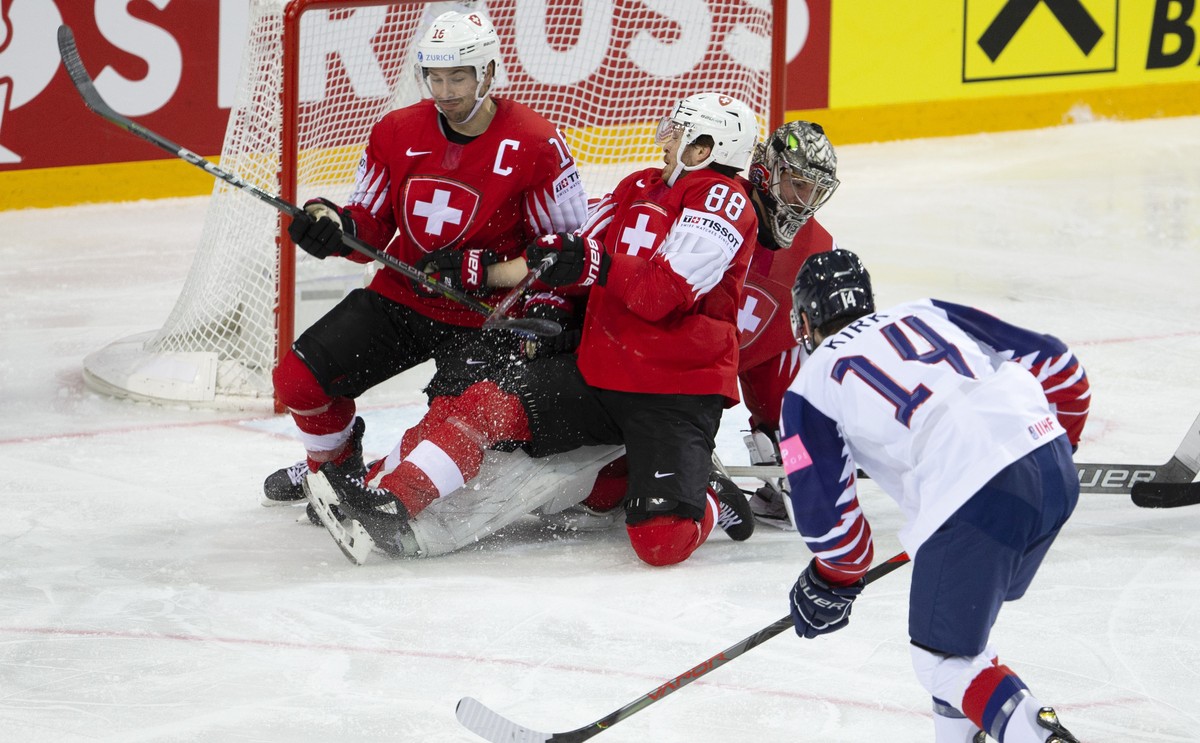 Great Britain's forward Liam Kirk #14 scores the 2:2 against Switzerland's players defender Raphael Diaz, left, forward Christoph Bertschy #88 and goaltender Reto Berra, during the IIHF 2021 ...