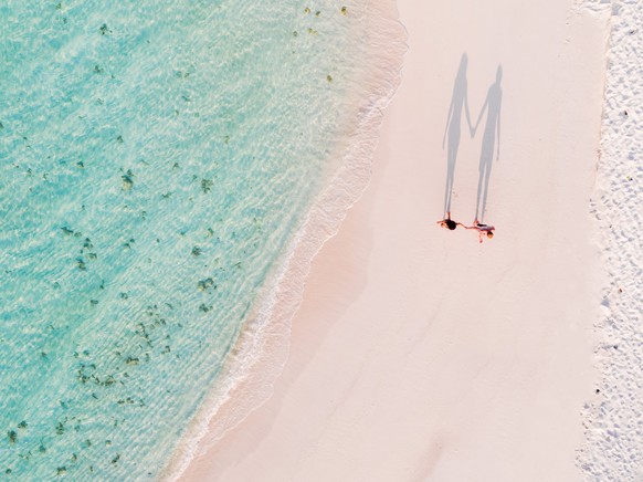 Aerial drone view of adult couple on a sandy beach, Maldives