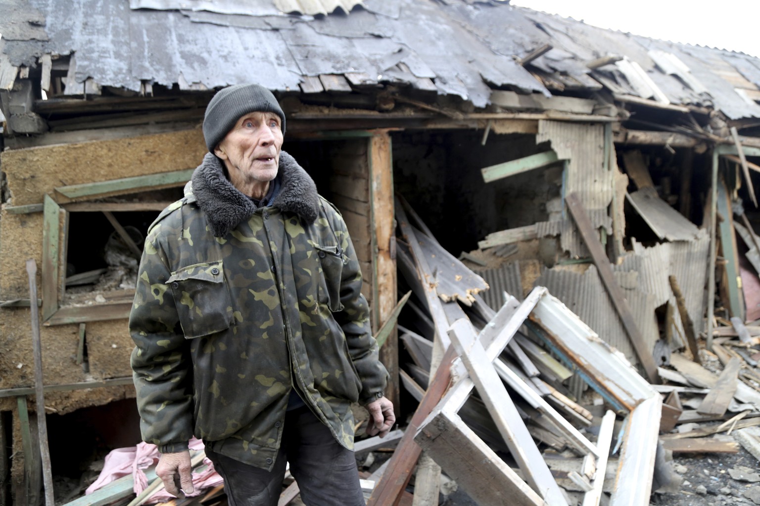 An elderly local citizen stands between debris of his house in the aftermath consequences of Ukrainian shelling, in the territory controlled by pro-Russian militants, eastern Ukraine, Thursday, Feb. 2 ...