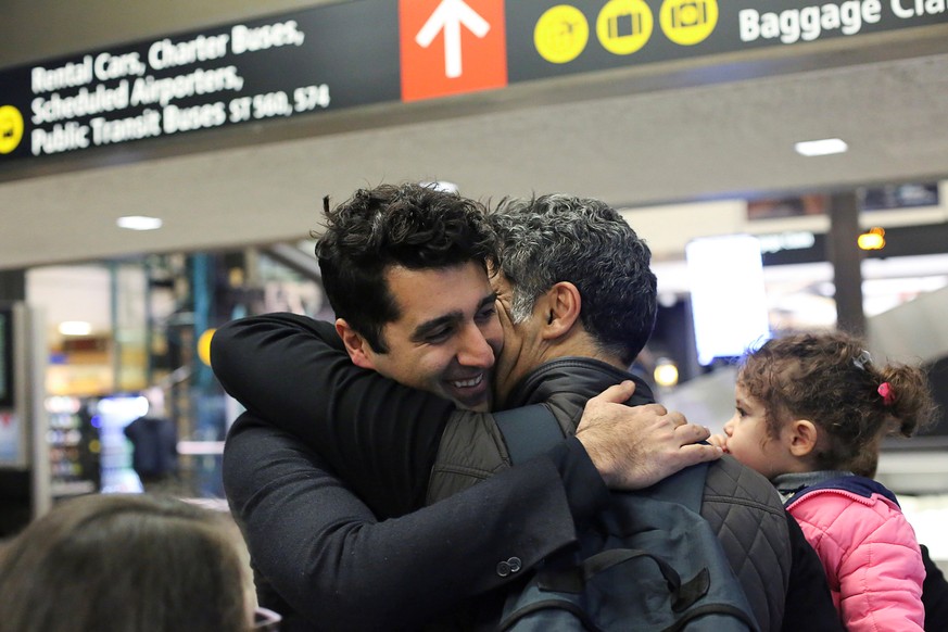 Iranian citizen and U.S green card holder Cyrus Khosravi (L) greets his brother, Hamidreza Khosravi (C), and niece, Dena Khosravi (R), 2, after they were detained for additional screening following th ...