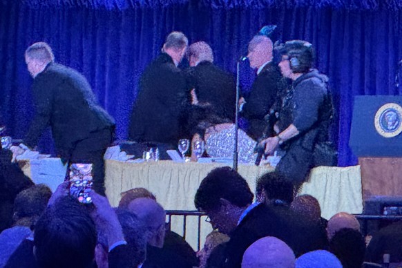 U.S. Secret Service agents surround President Donald Trump, third from left, as he is taken from the stage after a shooting incident outside the ballroom during the White House Correspondents Dinner,  ...