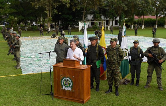 epa06316704 A handout photo made available by the Presidency of Colombiashows the Colombian President Juan Manuel Santos (R) speaking next to packages containing cocaine, in Apartado, in the Departmen ...