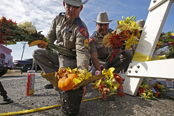 epa06312221 Texas State Troopers pick up flowers left for a memorial to move them out of the street near the church while investigators work at the scene of a mass shooting at the First Baptist Church ...
