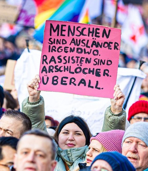 20.01.2024, Niedersachsen, Hannover: Zahlreiche Menschen nehmen an einer Demonstration gegen Rechtsextremismus auf dem Opernplatz teil - auf Plakaten sind die Schriftz