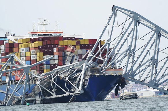 A cargo ship is trapped under part of the structure of the Francis Scott Key Bridge after the ship struck the bridge, Tuesday, March 26, 2024, in Baltimore, Virginia.  (AP Photo/Steve Helber)