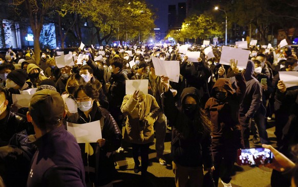 epa10332665 Protesters hold blank white pieces of paper during a protest triggered by a fire in Urumqi that killed 10 people in Beijing, China, 27 November 2022. Protests against?s China strict Covid  ...