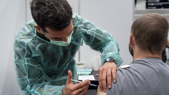 Ein Durchdienersoldat der Sanitaetsschule Airolo verabreicht eine Booster-Impfung mit dem Covid-19-Impfstoff im Impfzentrum in Delemont, am Dienstag, 14. Dezember 2021. (KEYSTONE/Georgios Kefalas)
