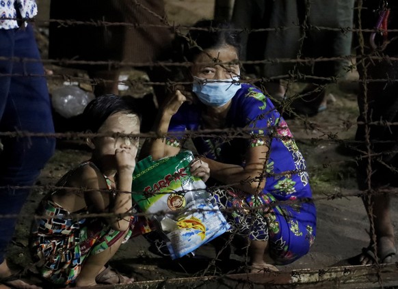 epa09530197 A woman and a girl wait for the released of their family member behind the barricade outside the Insein prison in Yangon, Myanmar, 18 October 2021. Myanmar&#039;s junta chief Min Aung Hali ...