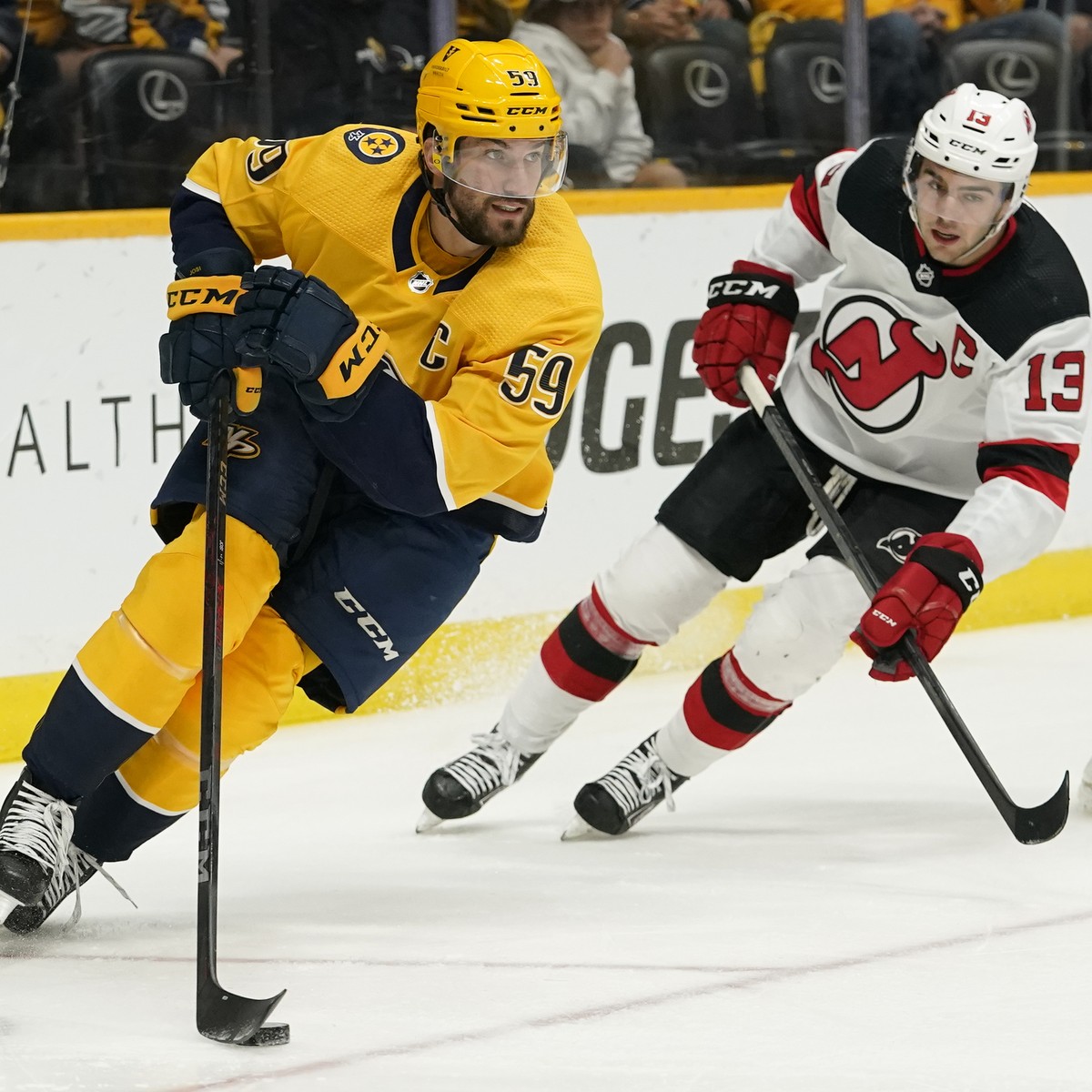 Nashville Predators defenseman Roman Josi (59) moves the puck ahead of New Jersey Devils center Nico Hischier (13) in the first period of an NHL hockey game Friday, Nov. 26, 2021, in Nashville, Tenn.  ...