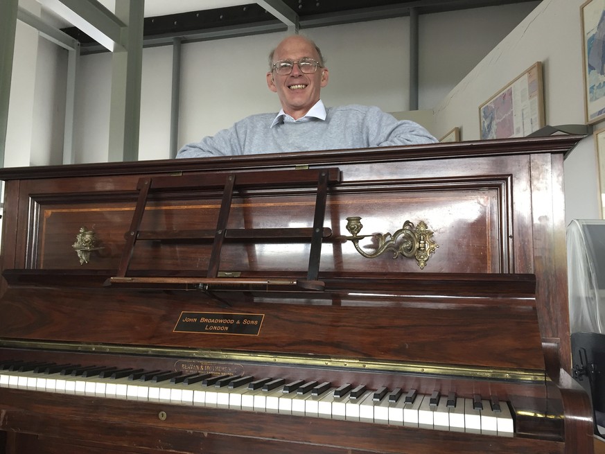 Piano tuner Martin Backhouse with the piano where he found a stash of gold, smiles in Ludlow Museum in Ludlow, England Thursday April 20, 2017, As a mystery surrounds the identity of the rightful heir ...