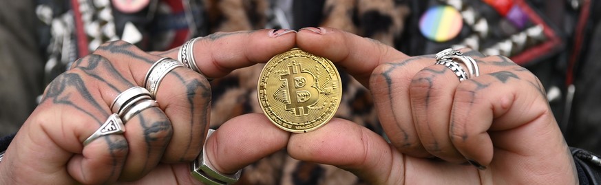 epaselect epa09600698 A performer holds a metal representation of a Bitcoin during a photocall in front of the Tower of London in London, Britain, 24 November 2021. The photocall was organized to cele ...