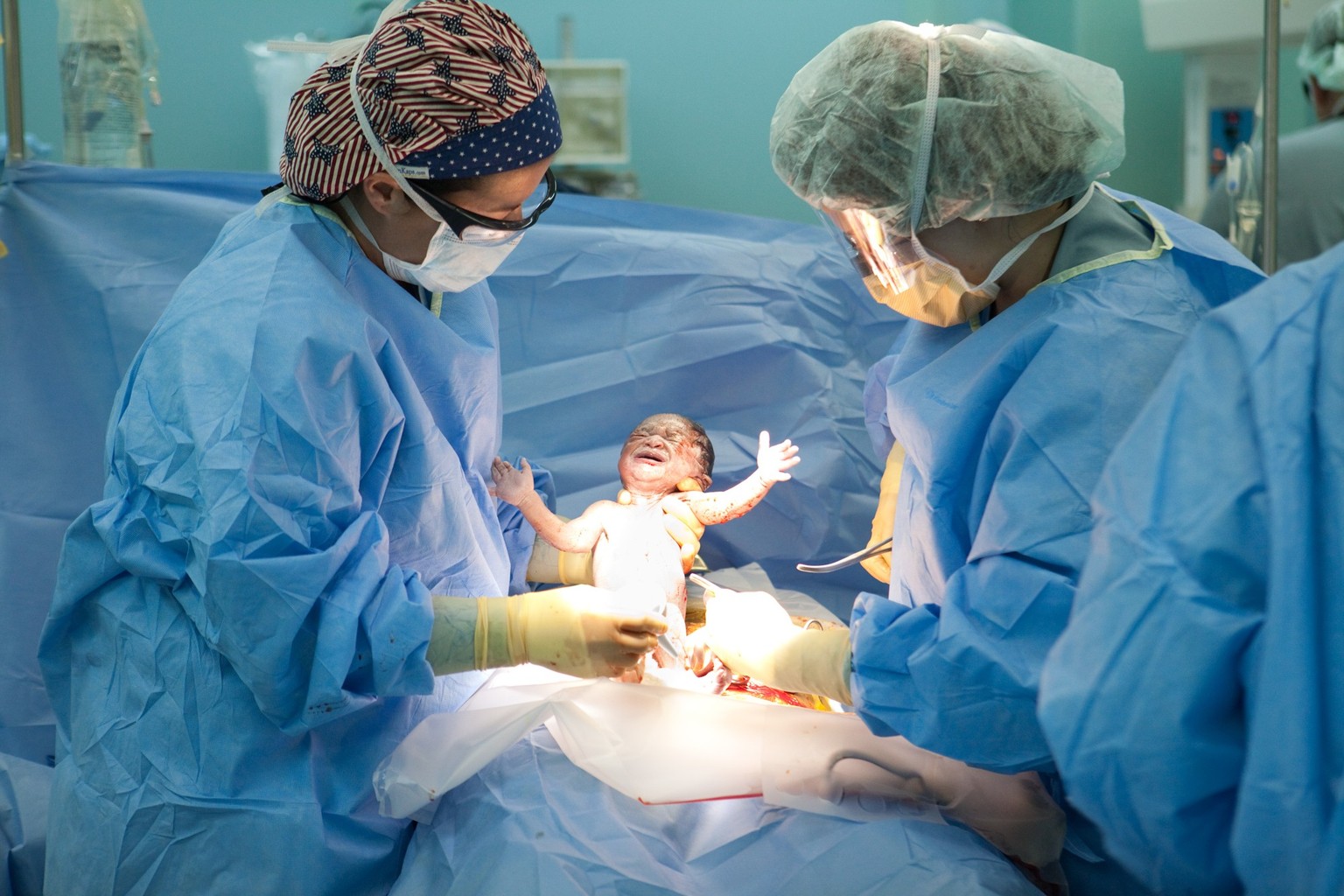 PORT-AU-PRINCE, HAITI - JANUARY 21: Doctors Susan Farrar (L) and Shannon Lamb (R) deliver a baby girl named Esther by C-section on board the USNS Comfort, a U.S. Naval hospital ship, on January 21, 20 ...