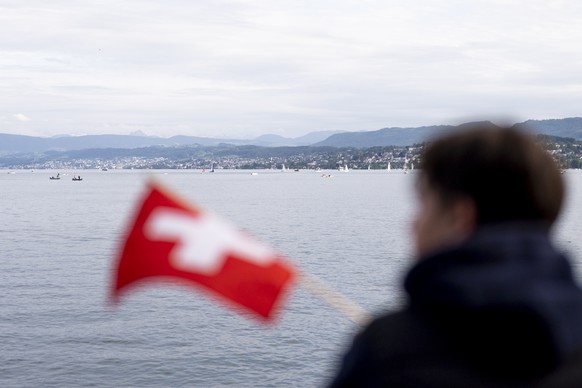 Ein Kind mit einer Schweizerfahne schaut auf den Zuerichsee, am Donnerstag, 29. Mai 2025 in Zuerich. (KEYSTONE/Til Buergy).