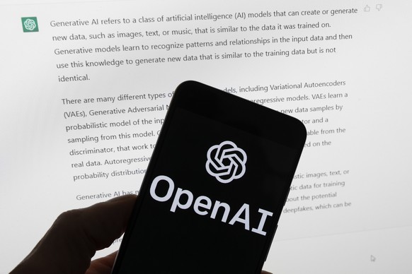 FILE - The OpenAI logo is seen on a mobile phone in front of a computer screen displaying output from ChatGPT, Tuesday, March 21, 2023, in Boston. Are tech companies moving too fast in rolling out pow ...