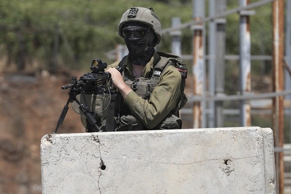 An Israeli soldier secures the entrance to the West Bank city of Hebron, a day after a deadly shooting attack that killed an Israeli woman and seriously wounded a man near the city, Tuesday, Aug. 22,  ...