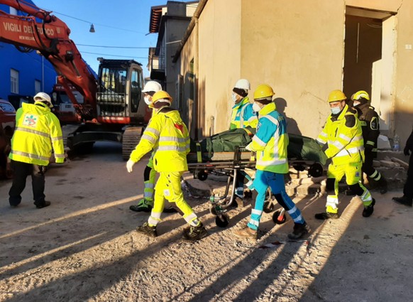 epa09639816 Rescue teams evacuate a body from the scene of a blast caused by a gas leak in Ravanusa, Sicily, Italy, 13 December 2021. Firefighters found a fourth body in the rubble of the collapsed bu ...