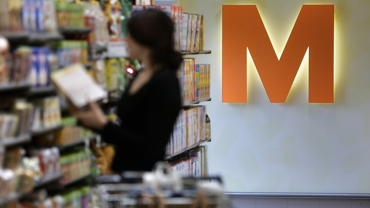 Eine Frau begutachtet am 9. Maerz 2005 in der Migros-Filiale in Embrach ein Produkt. Das orange M prangt auf der Wand hinter ihr. (KEYSTONE/Gaetan Bally)