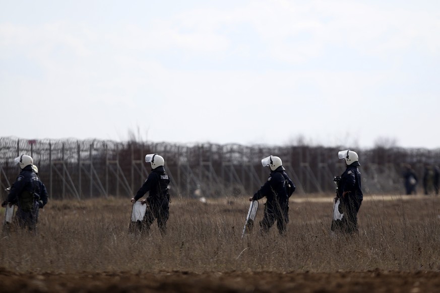 Greek riot policemen guard as migrants gather near the Kastanies border gate at the Greek-Turkish border, Sunday, March 1, 2020. Thousands migrants massed at the Turkish-Greek border, and hundreds mor ...