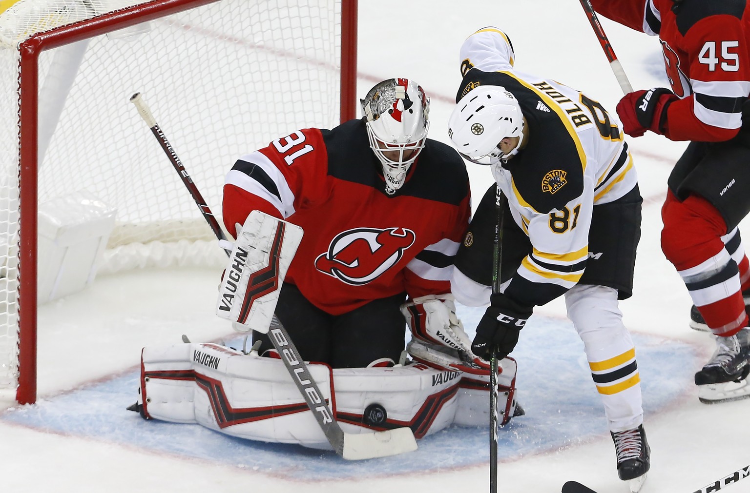 New Jersey Devils goaltender Gilles Senn (31) makes a save against Boston Bruins left wing Anton Blidh (81) during the third period of an NHL preseason hockey game, Monday, Sept. 16, 2019, in Newark,  ...